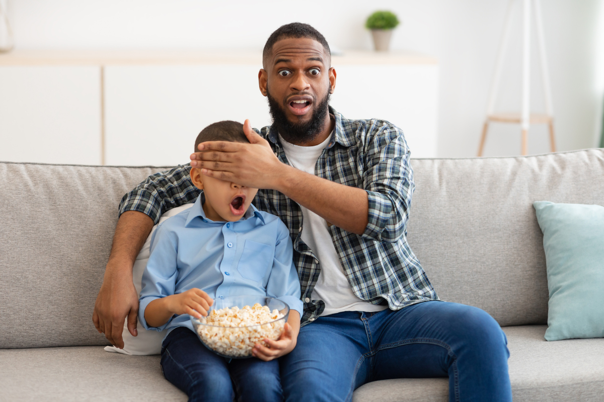 Vater und Sohn schauen mit Popcornerstaunt fern